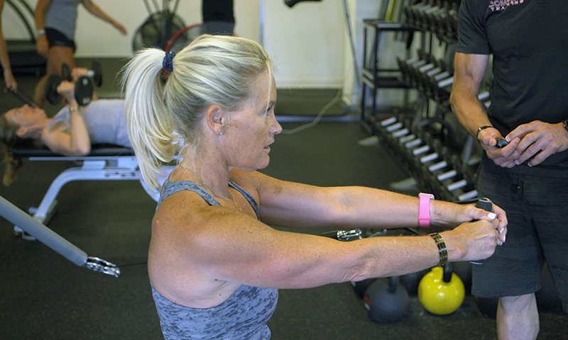 A woman is holding onto a kettlebell in the gym.